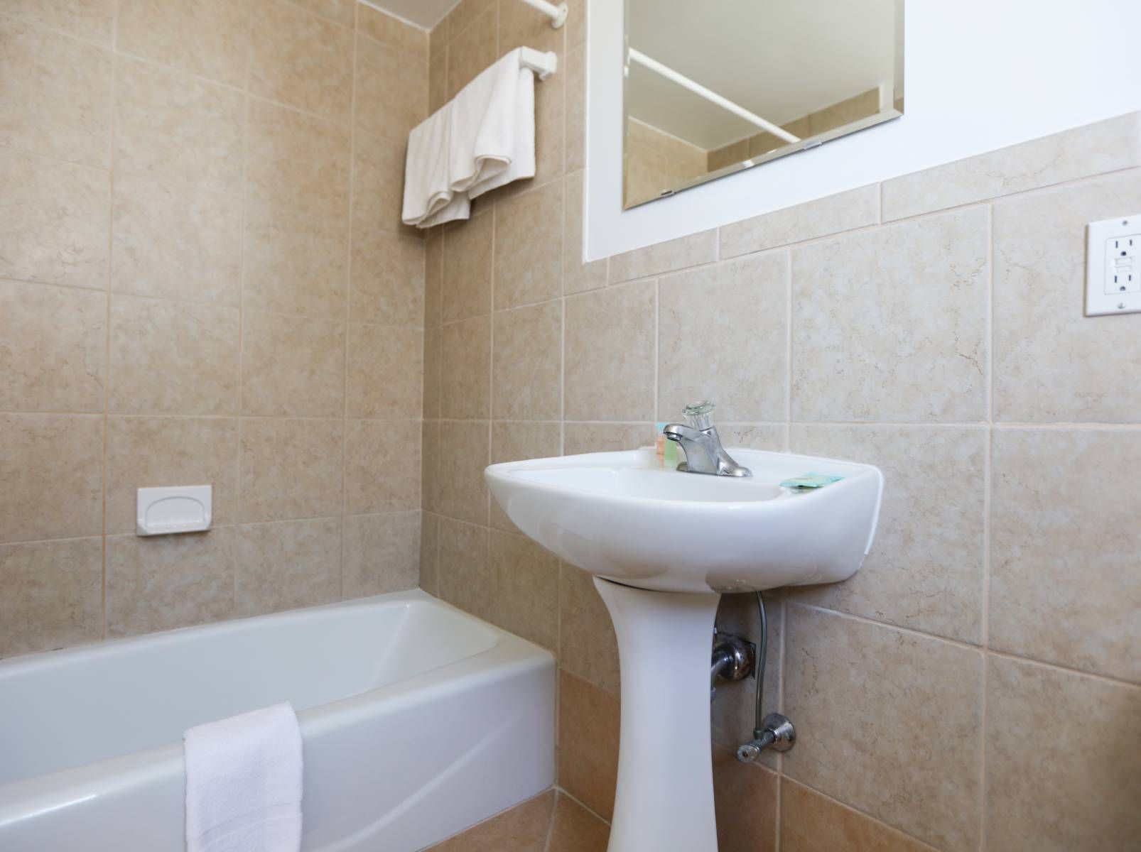 A bathroom with a sink , tub and mirror