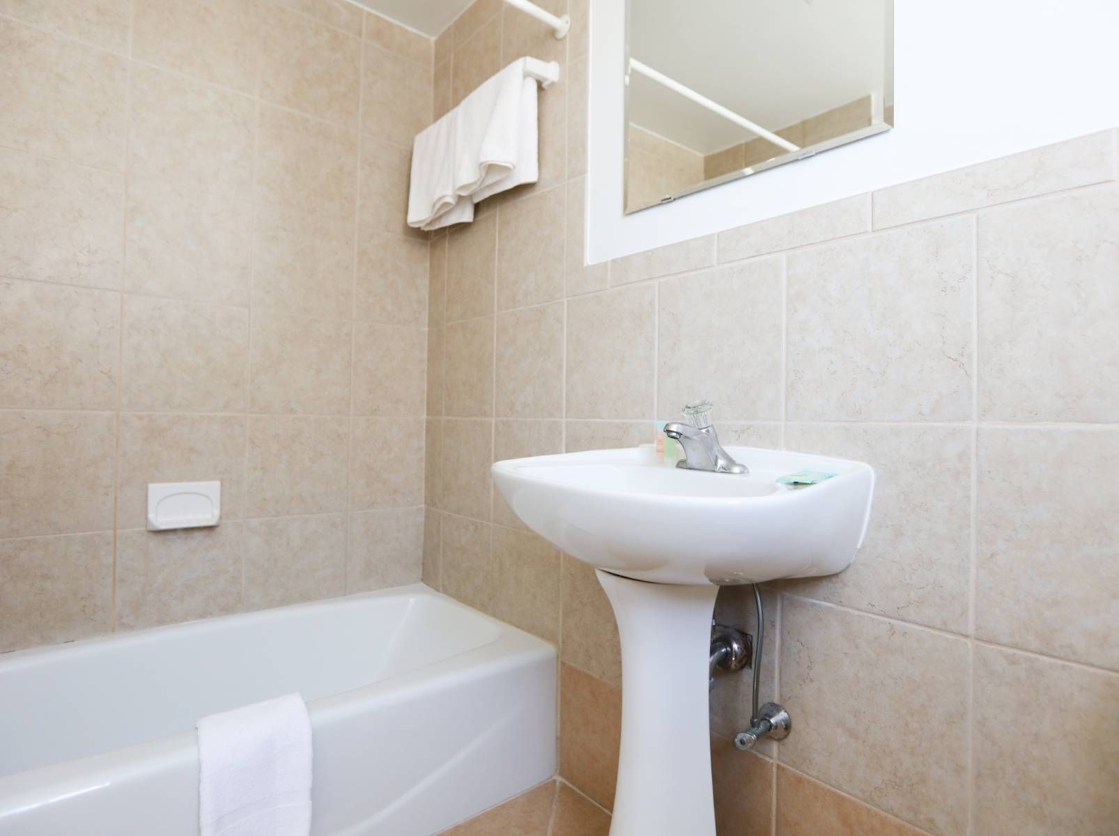A bathroom with a sink , tub and mirror.
