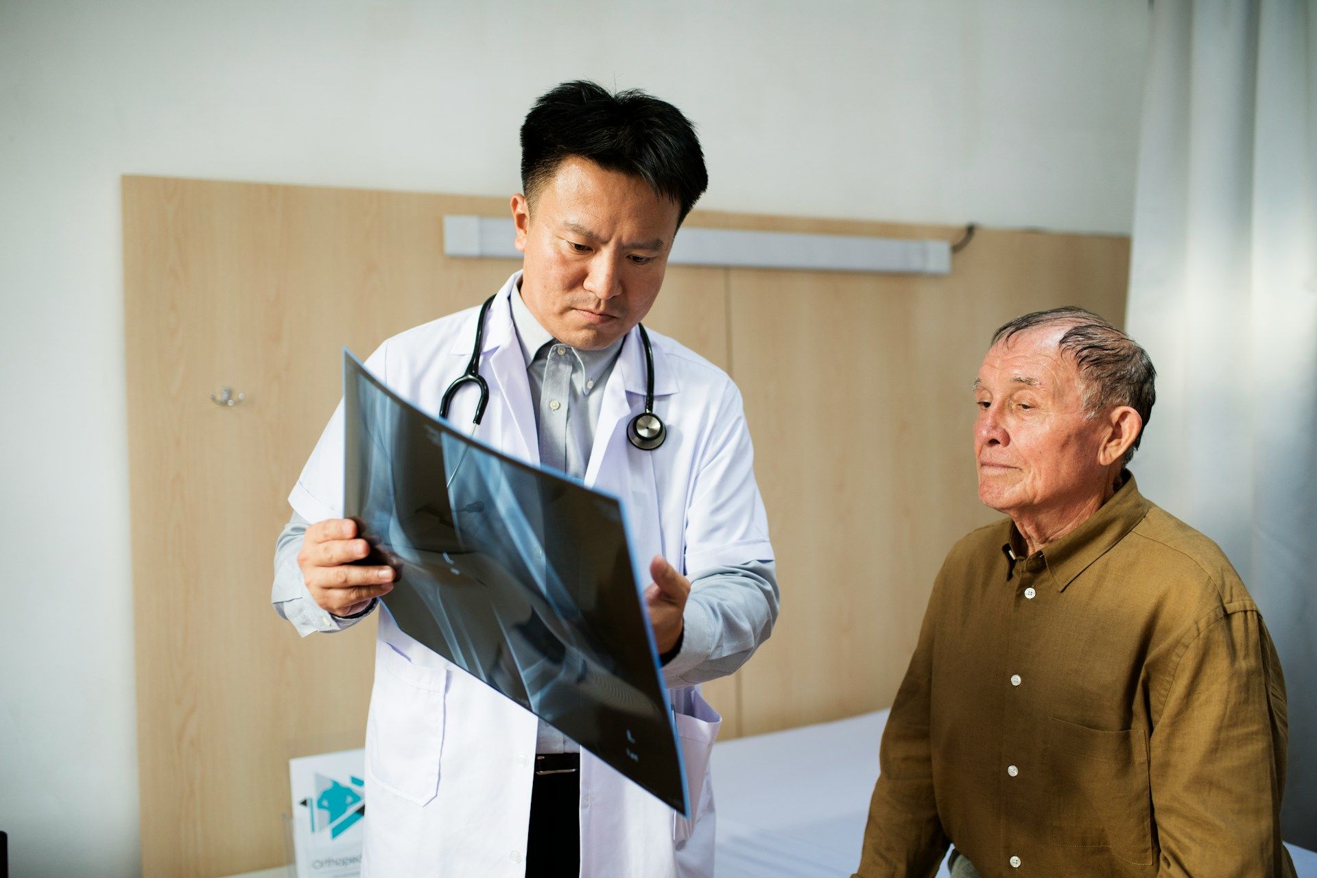 Caregiver assisting an elderly man in a wheelchair, smiling in a brightly lit room.