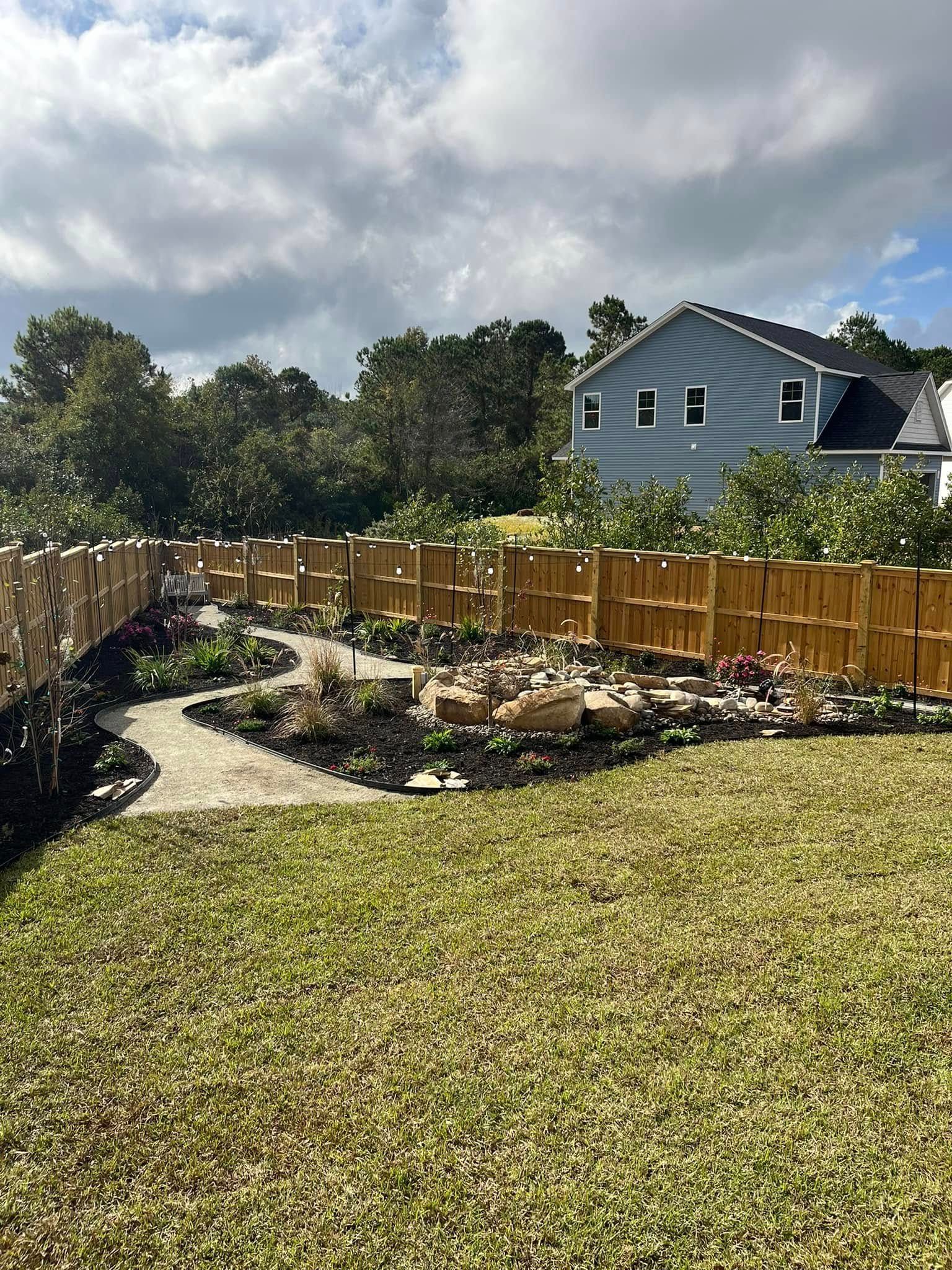 A backyard with a wooden fence and a house in the background.