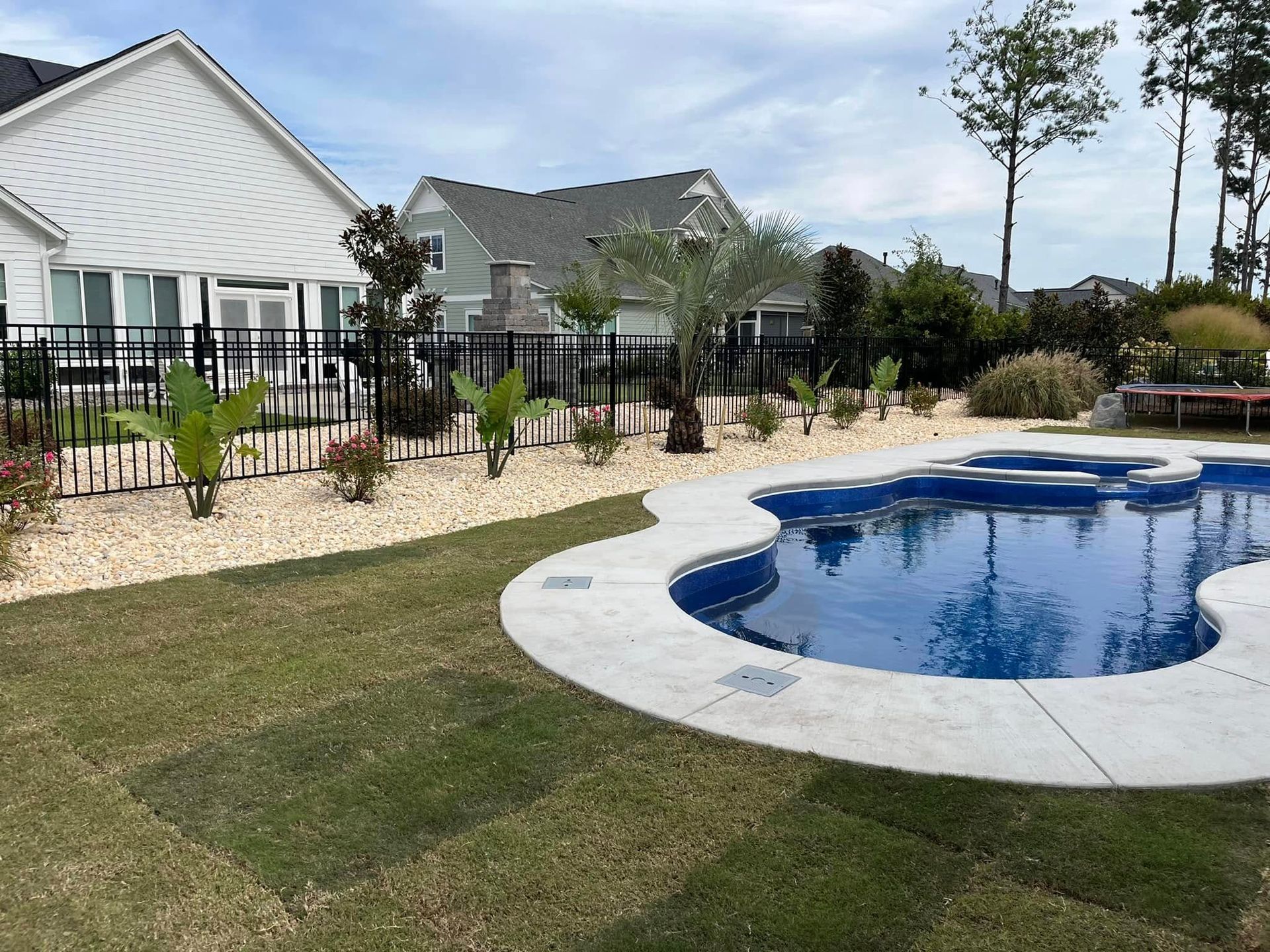 A large swimming pool is in the backyard of a house.