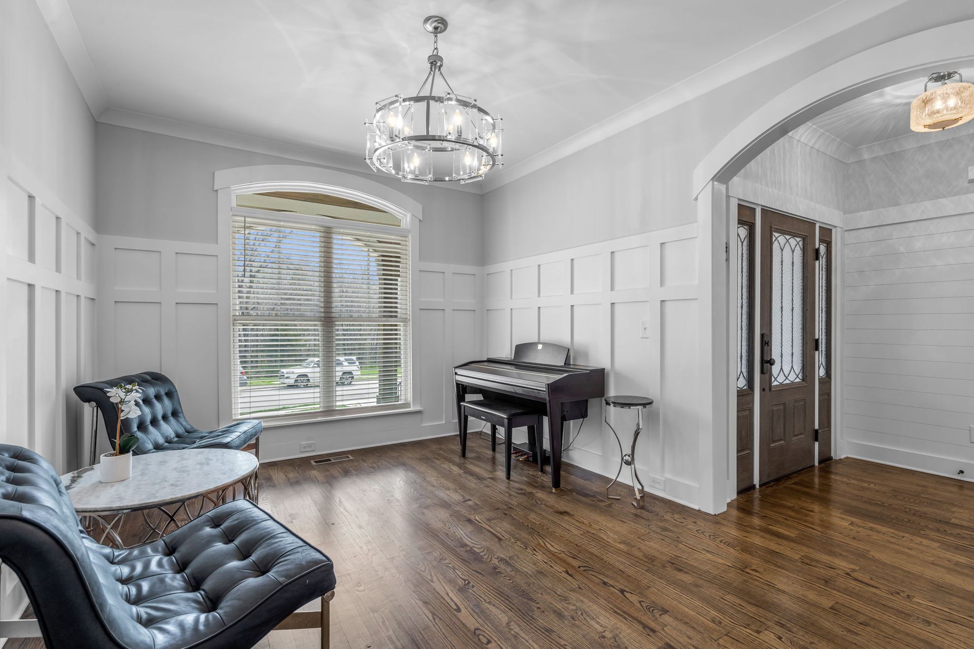 Custom home builder in Chattanooga designs elegant sitting room with wainscoting, chandelier, and piano nook.