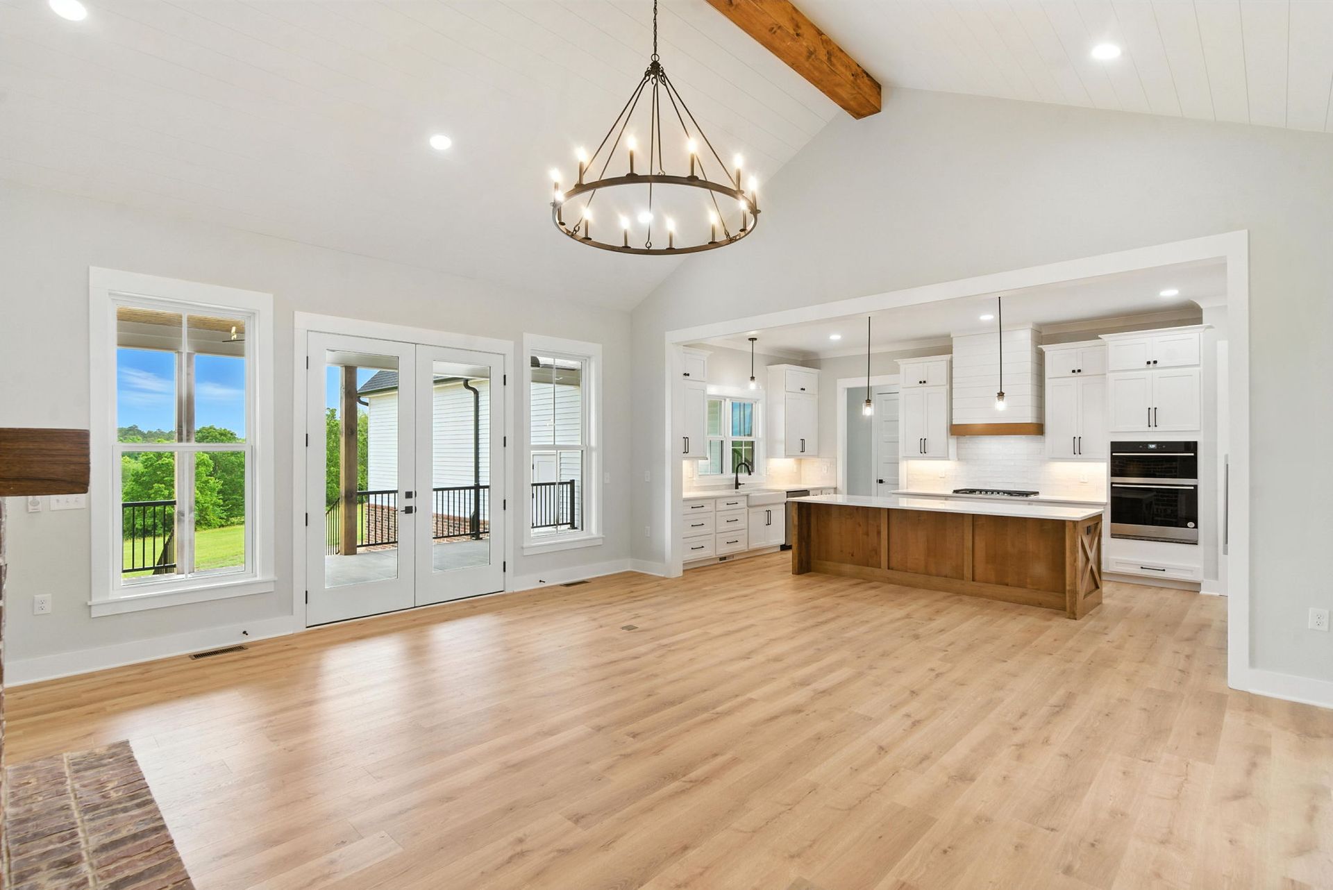 Spacious bright kitchen and living area with light wood floors, white cabinets, and large windows