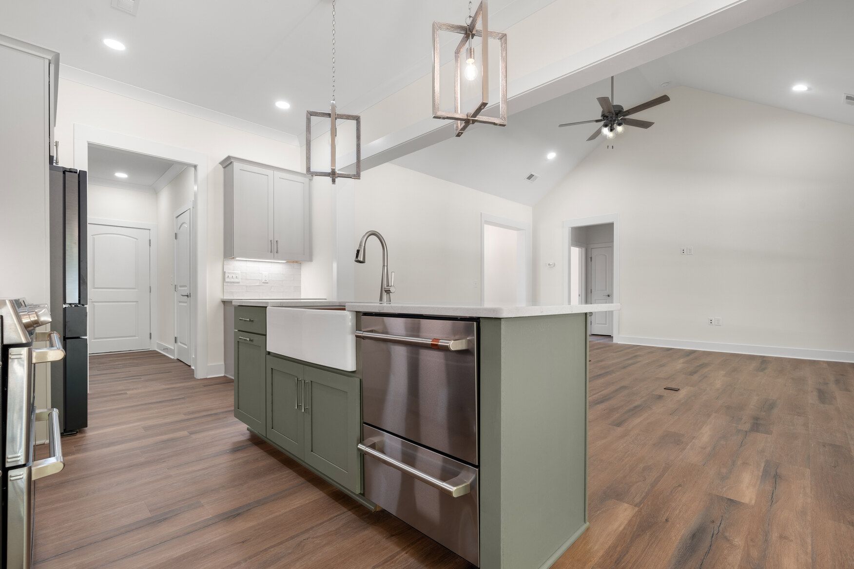Modern open-concept kitchen with island, white cabinets, wood floors, and pendant lights