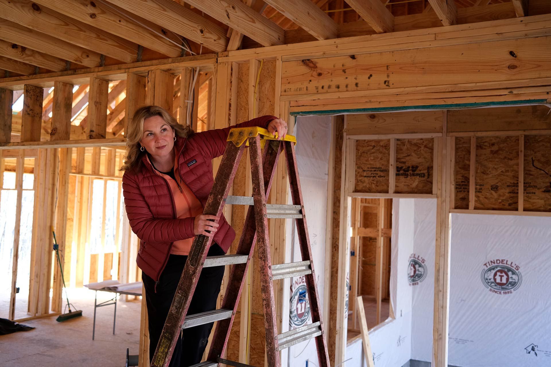 Collette Branham on a ladder inspecting framing at a TriStar custom home build in Chattanooga