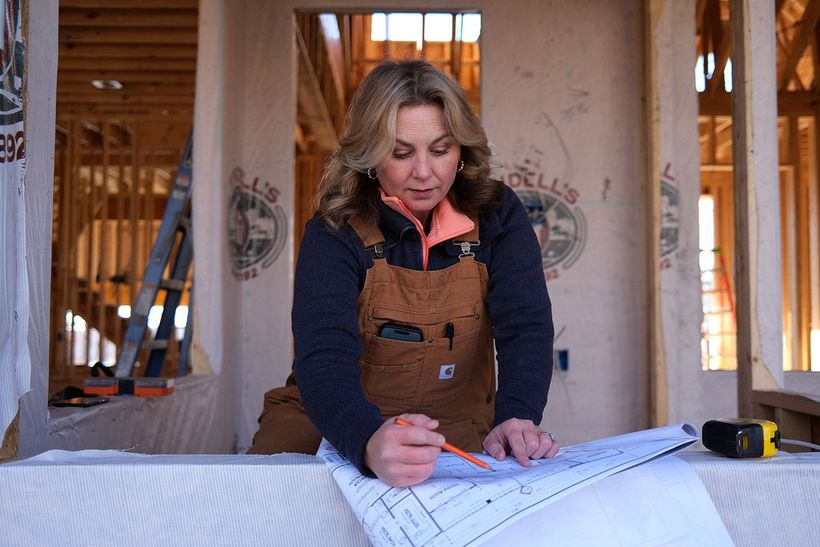 Collette Branham, owner of Tristar Custom Homes, smiling and holding blueprints on a job site in Chattanooga — custom home builder Chattanooga.