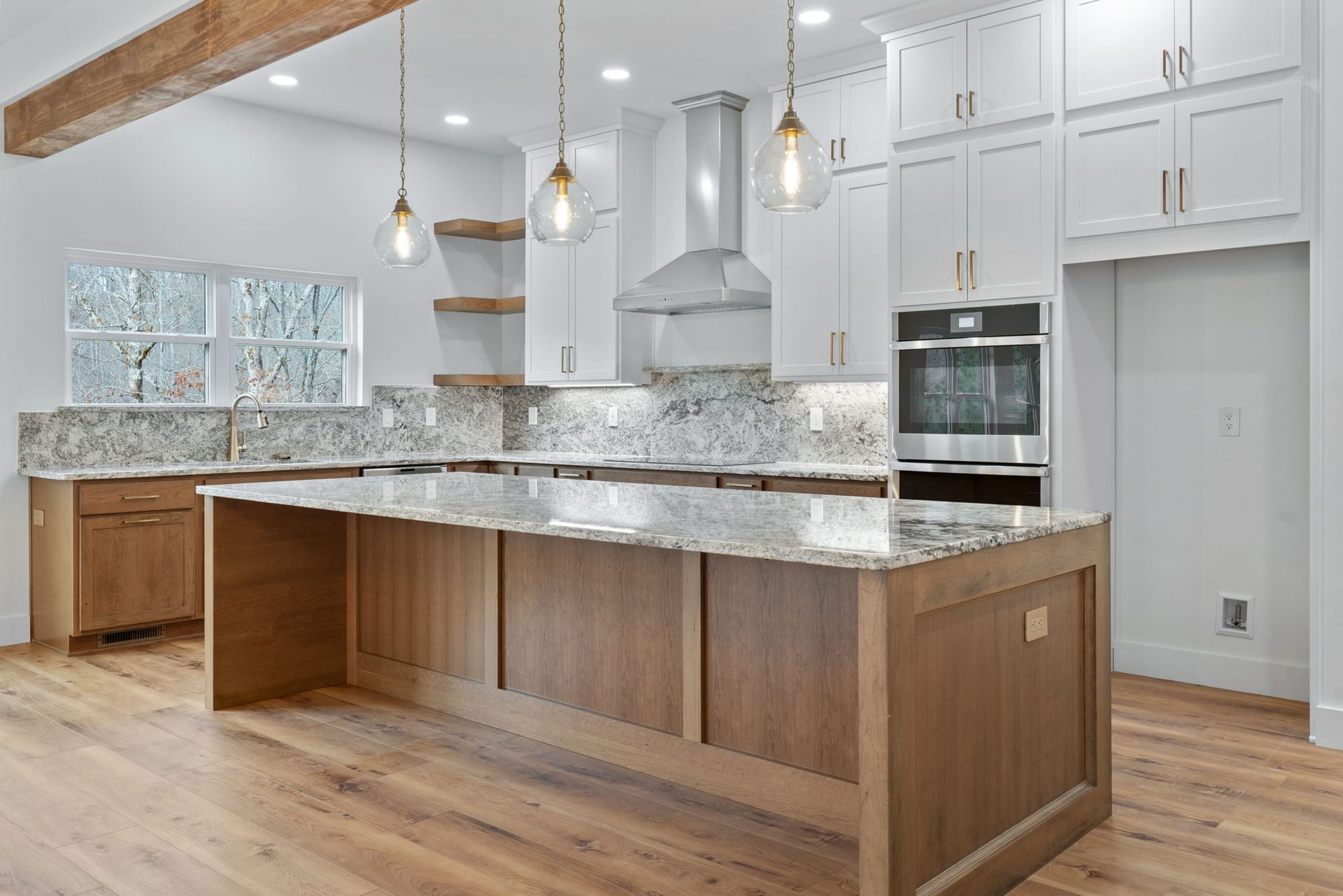 Bright and spacious custom kitchen featuring granite countertops, white shaker cabinets, and warm wood accents by a custom home builder in Chattanooga.