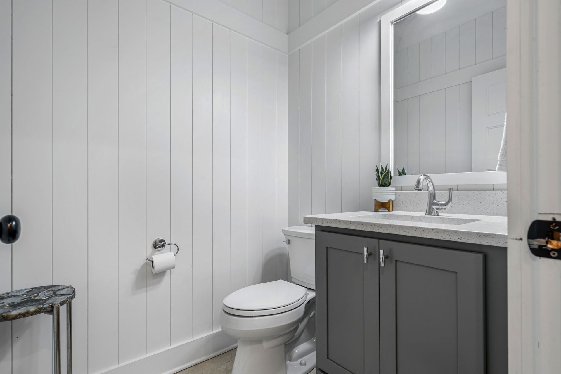 Custom home builder in Chattanooga showcases a modern bathroom with shiplap walls, quartz countertop, and gray vanity.