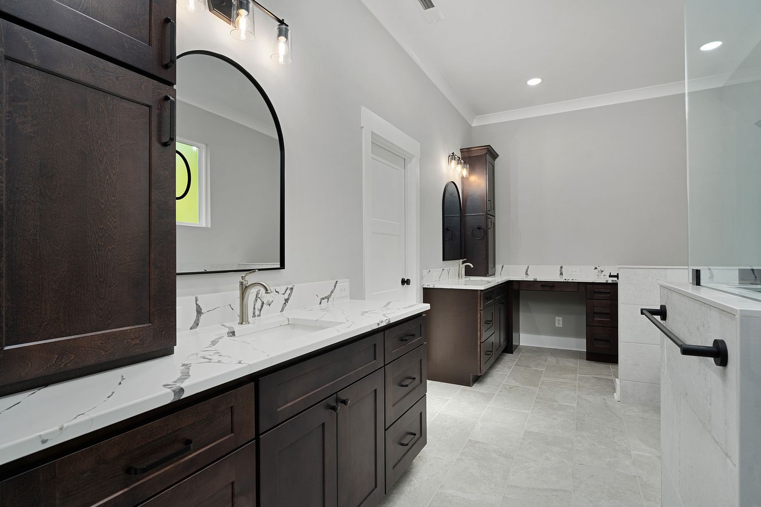 Modern bathroom with dark wood vanity, white marble counters, and large mirror in gray walls