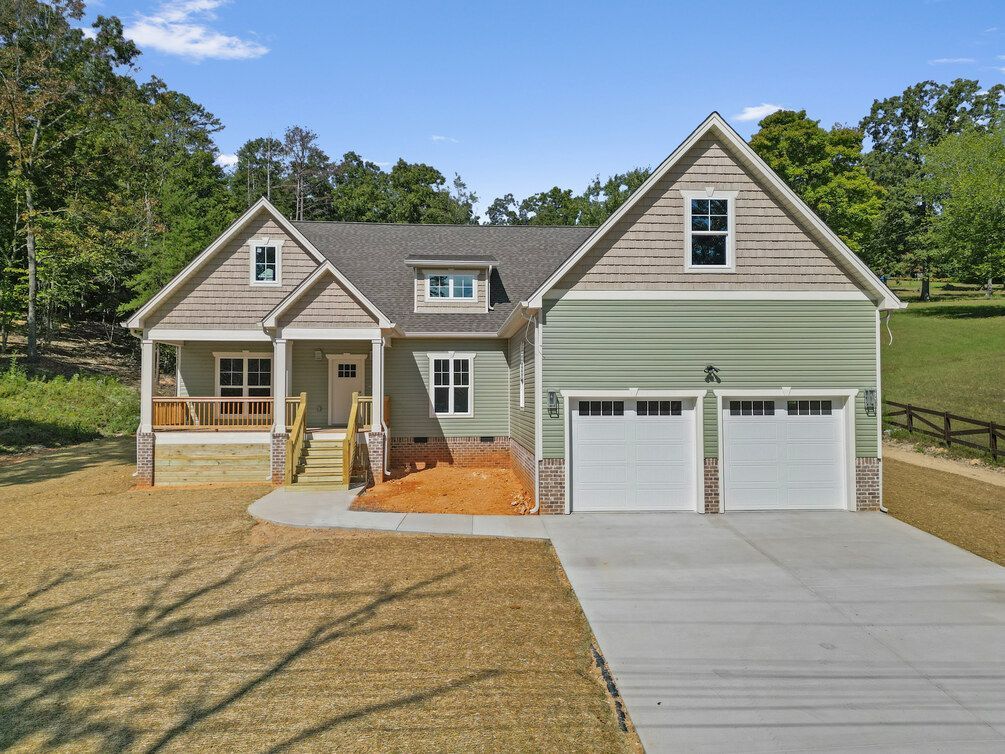 Suburban house with beige siding, two-car garage, and a concrete driveway under a clear blue sky