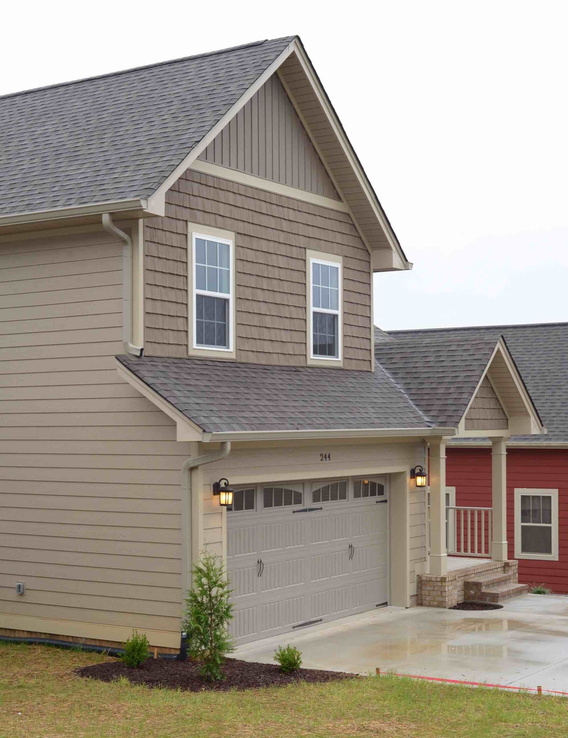New beige two-story house with gray roof and attached garage in a suburban neighborhood