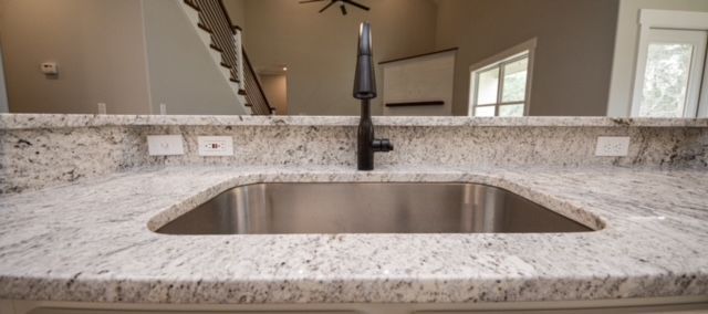Modern kitchen sink with granite countertop and black faucet, viewed from the front