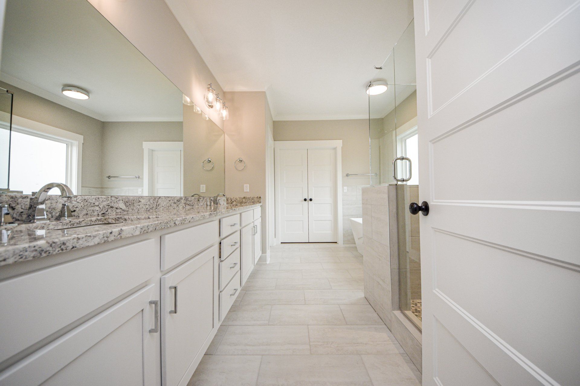 Spacious modern bathroom with double vanity, granite countertops, walk-in shower, and soaking tub in Chattanooga remodel.