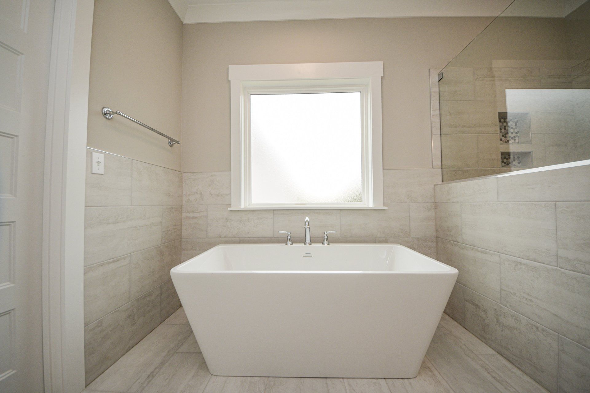 Modern bathroom with freestanding soaking tub and neutral tile surround in Chattanooga home remodel.