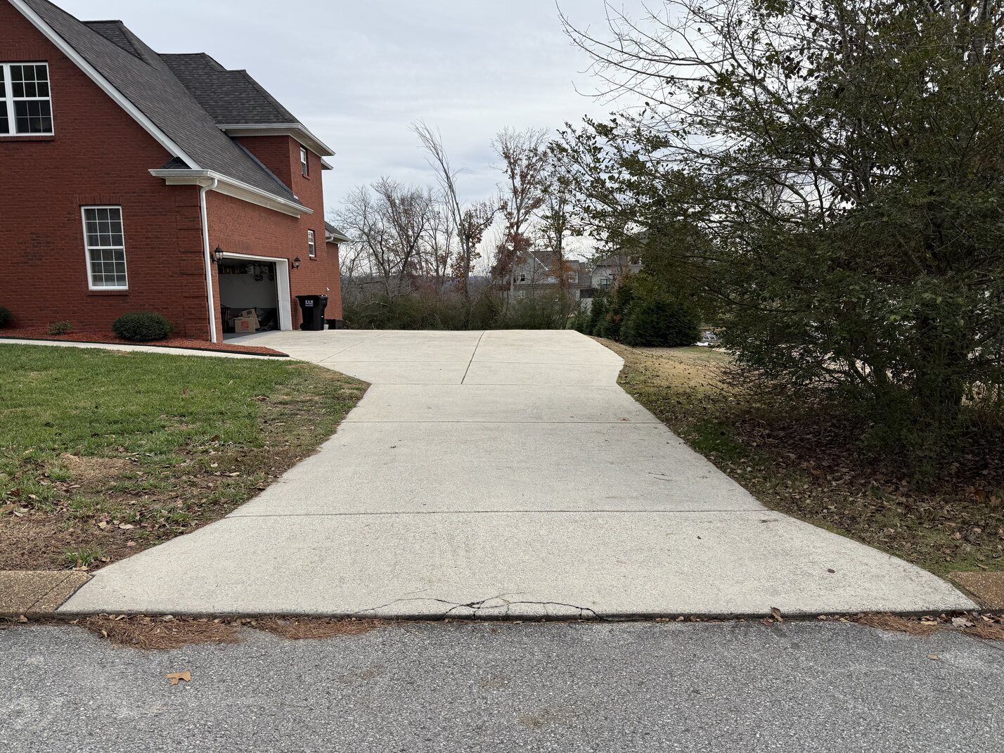 Concrete driveway leading to a red brick house beside a grassy yard