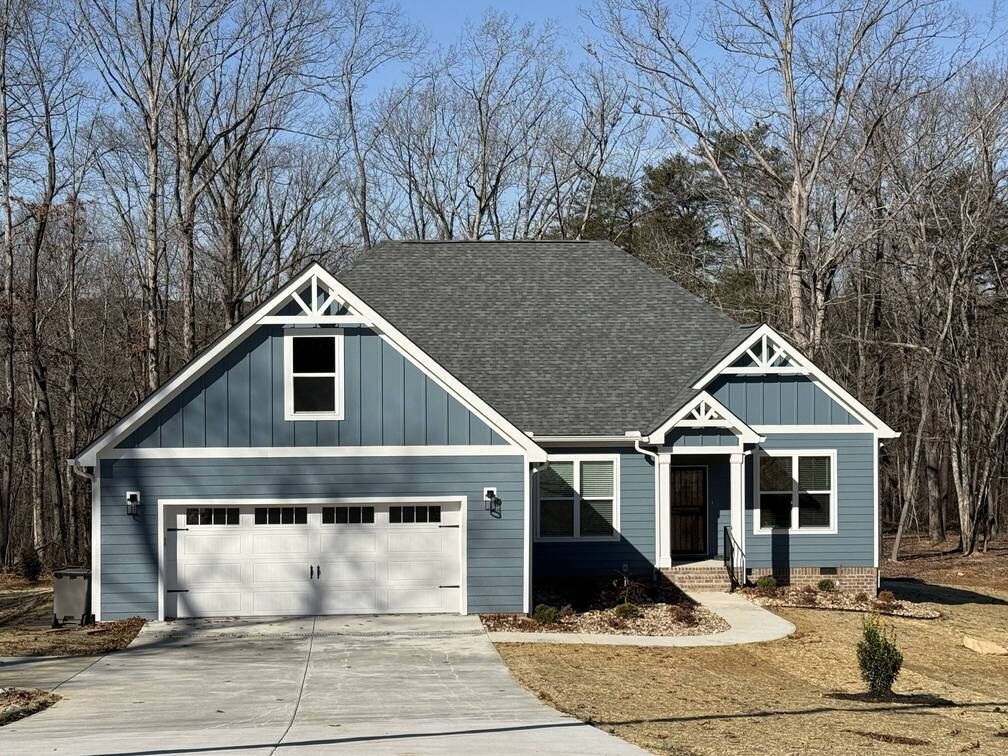 Blue suburban house with white trim, two-car garage, and a front yard by leafless trees