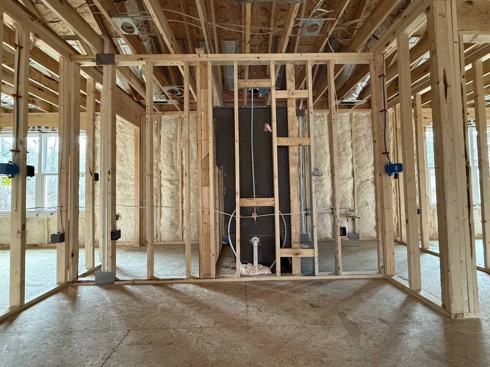 Framed house interior under construction with exposed wood studs and unfinished flooring