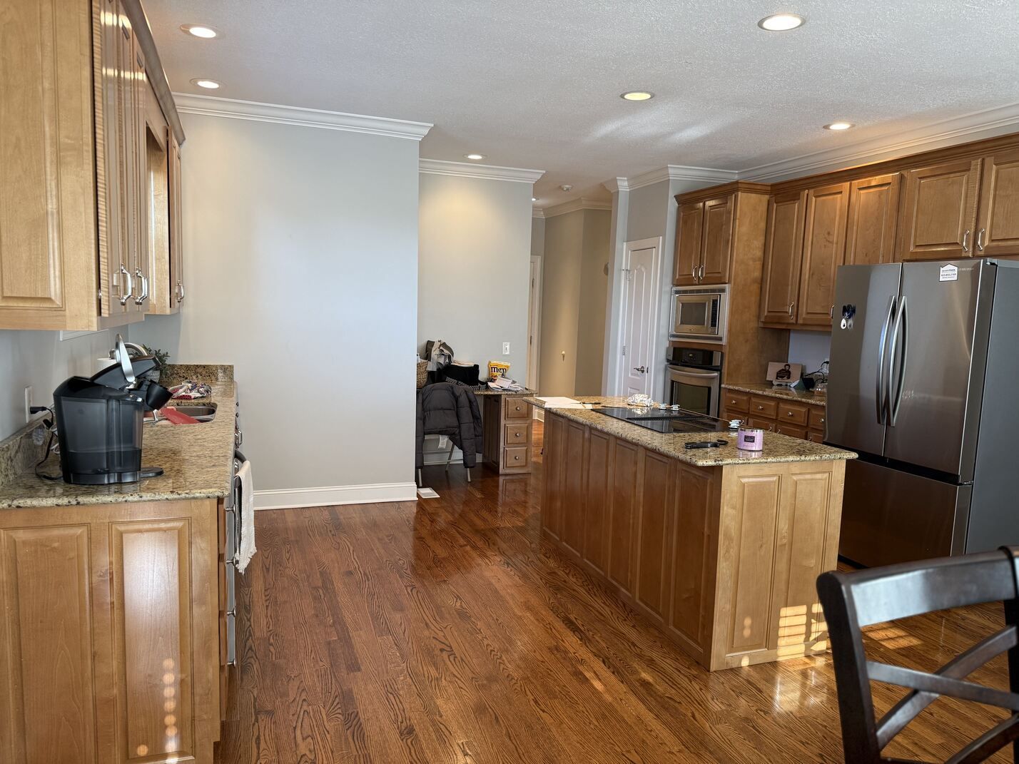 Spacious kitchen with wood cabinets, stainless steel fridge, island, and hardwood floors