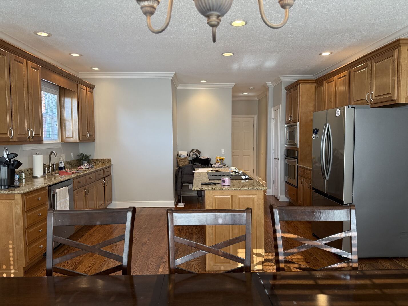 Kitchen with wooden cabinets, stainless steel fridge, and a dining table in the foreground.