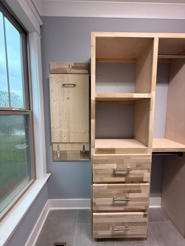 Built-in closet with drawers and shelves beside a window in a bright empty room