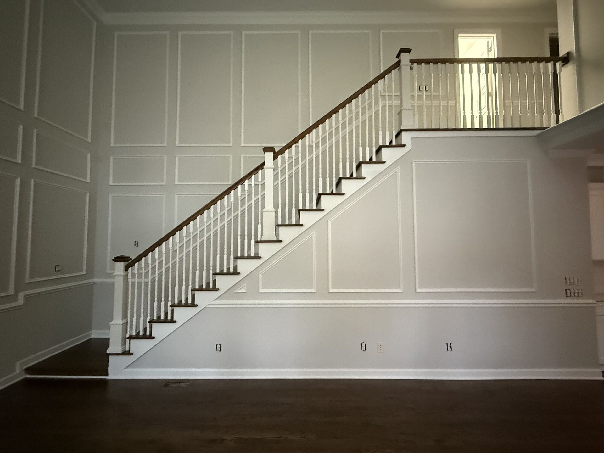 Interior staircase with white railing and wainscoted walls in a formal room