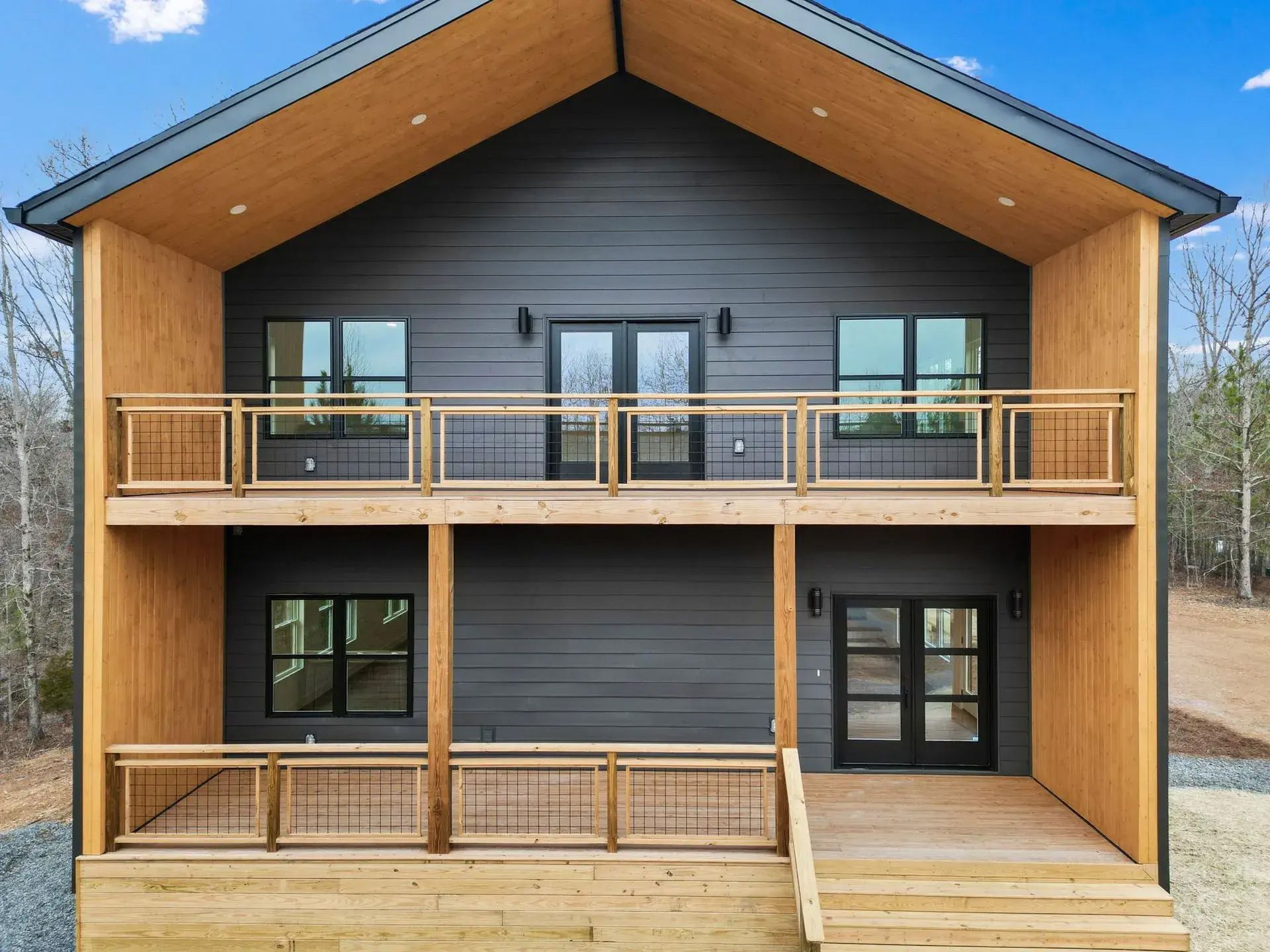 Modern two-story house exterior with gray siding, wood accents, and covered front porches