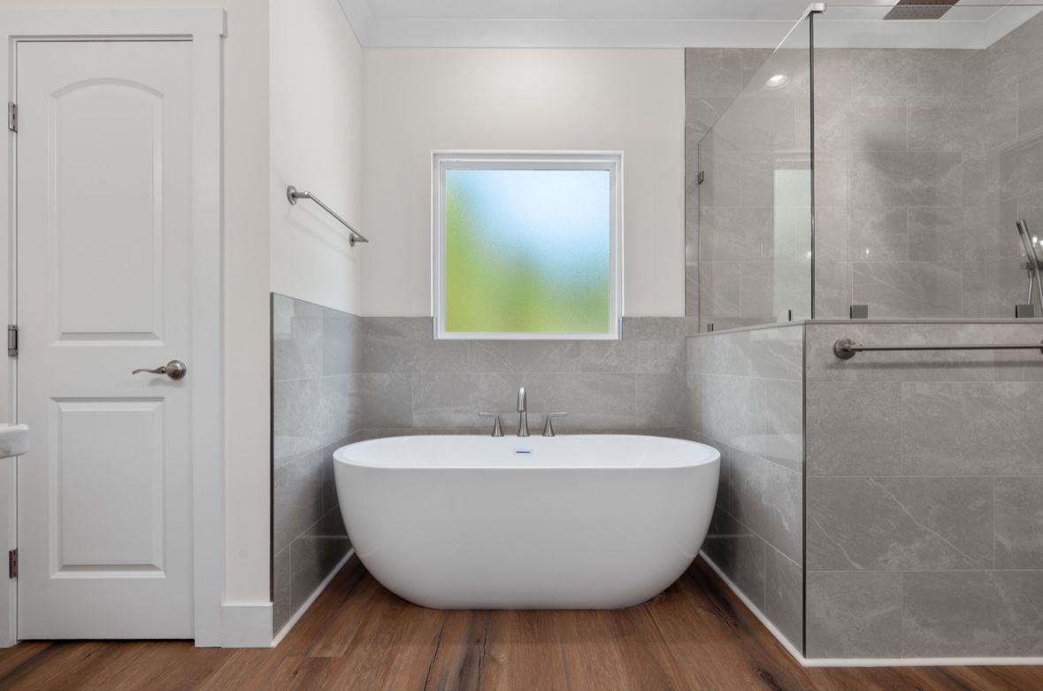Modern bathroom with freestanding tub, wood-look floors, and a tiled walk-in shower crafted by a custom home builder in Chattanooga.