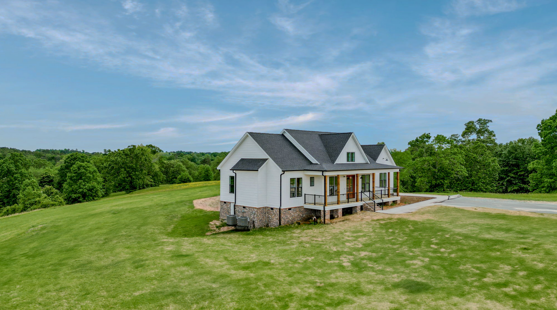 White house with gray roof on a grassy hillside under a blue sky