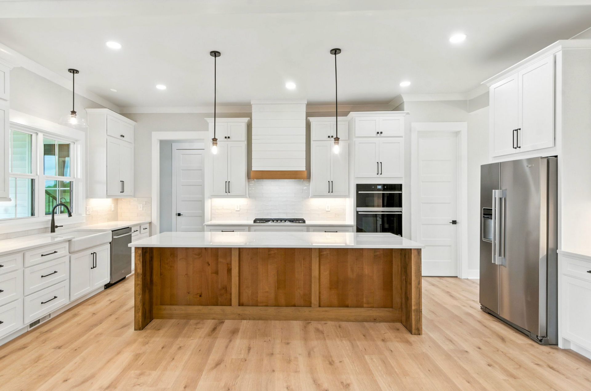 Bright modern kitchen with white cabinets, stainless appliances, and a large wood island