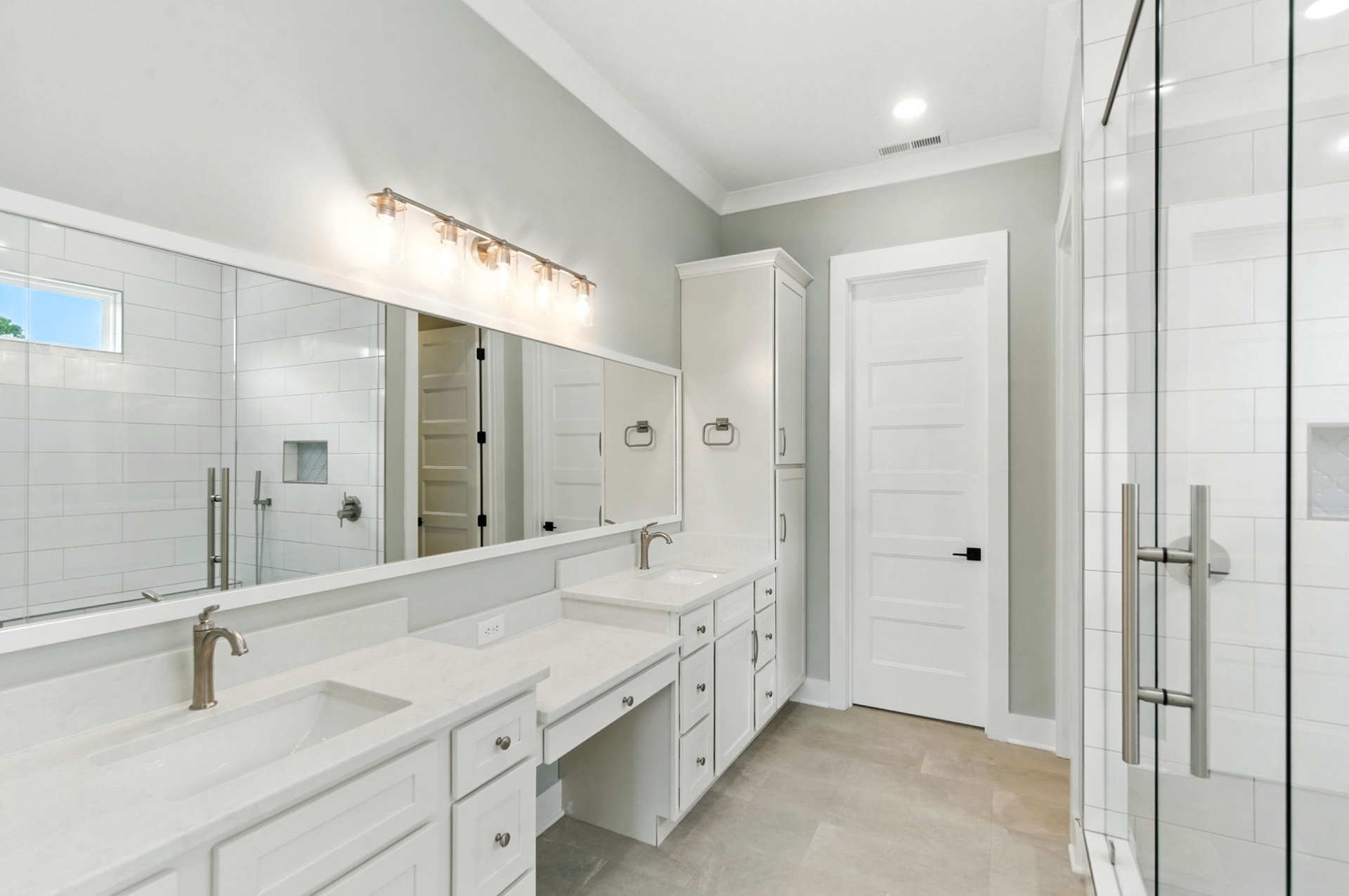 Bright white modern bathroom with double vanity, large mirror, walk-in shower, and glass-enclosed shower stall.