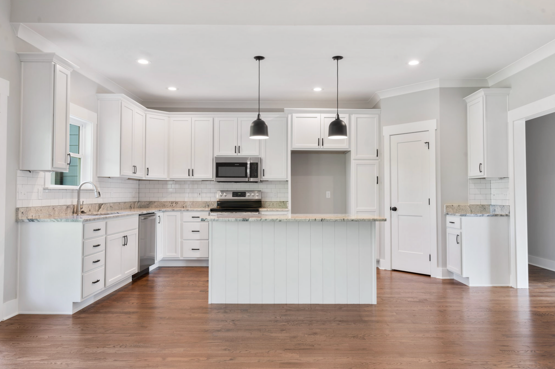 Bright white modern kitchen with island, stainless appliances, and wood floors