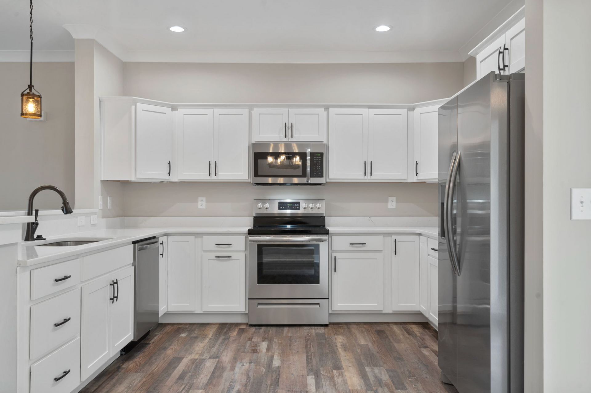 Bright modern kitchen with white cabinets, stainless steel appliances, and wood-look flooring