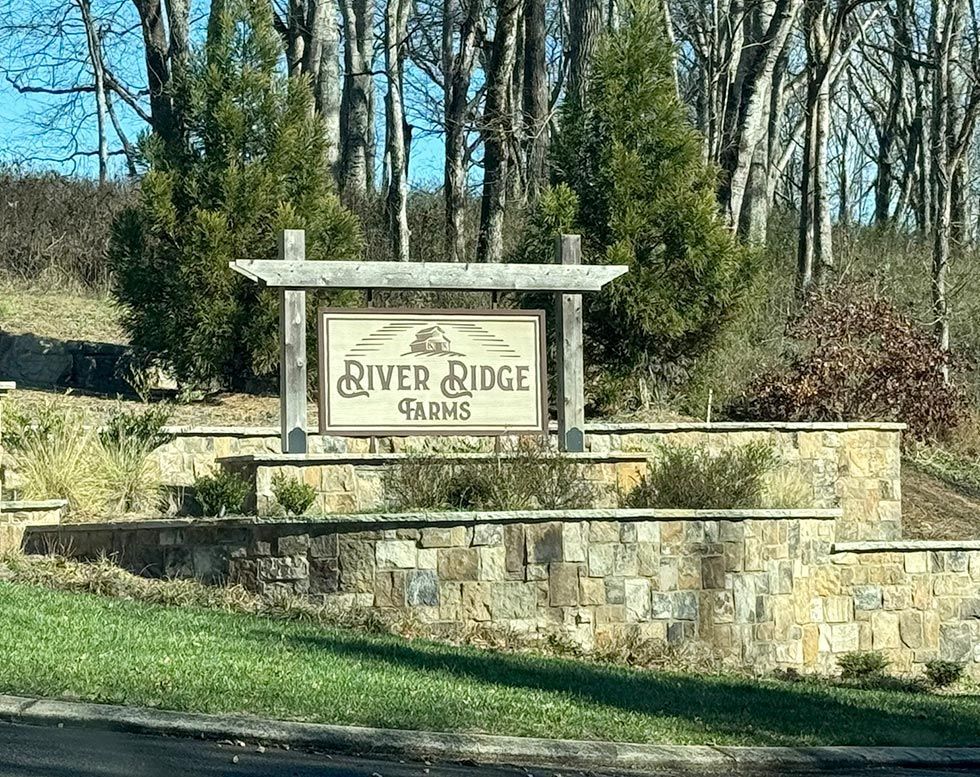 Stone sign for Silver Ridge Farms beside a road, with trees and grass in the background