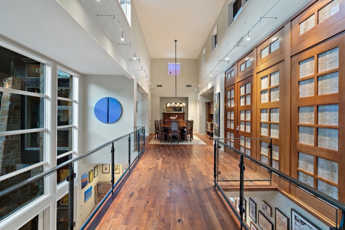 Interior view of a two-story hallway with a wooden floor and large doors on one side.