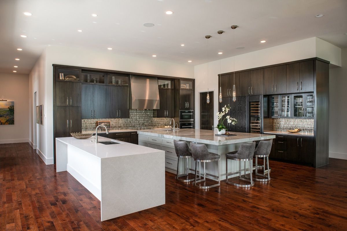 Modern kitchen with dark wood cabinets, white islands, and wood floors.