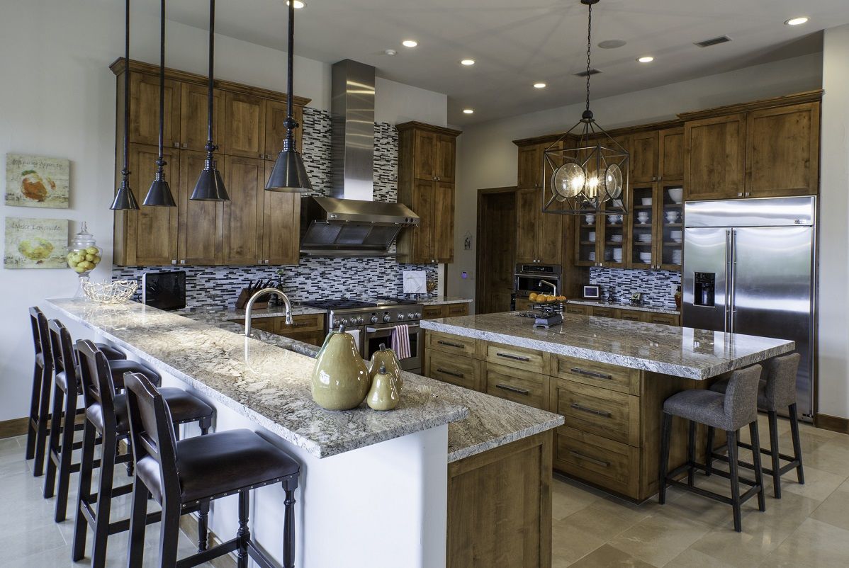 Spacious kitchen with wood cabinets, granite counters, and an island. Bar stools, stainless steel appliances.
