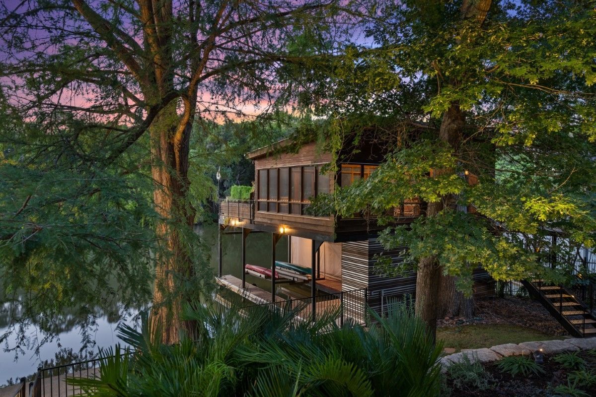 Wooden boathouse on a lake, surrounded by trees, during dusk.