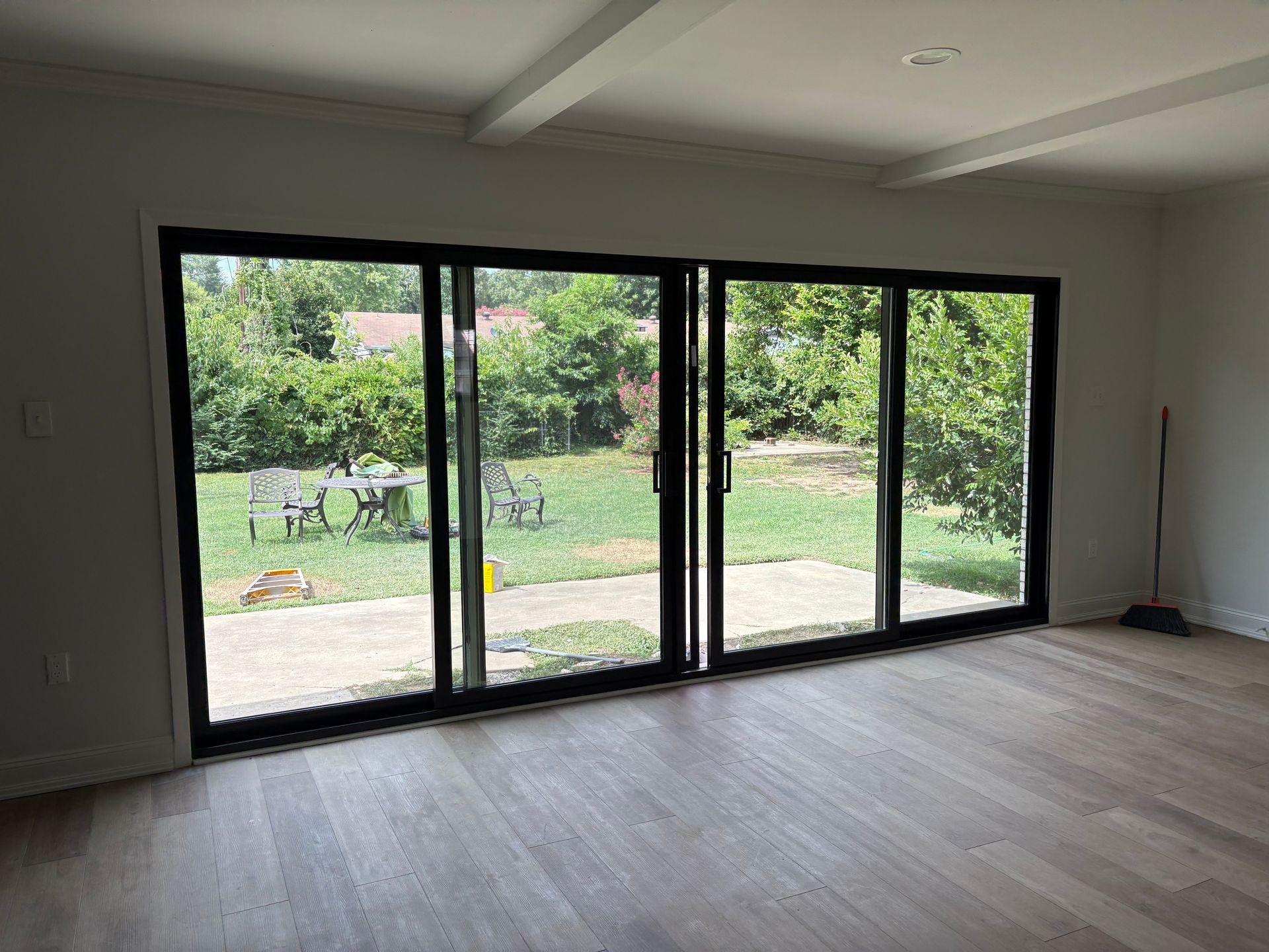 Living room with large sliding glass doors overlooking a backyard with trees and a table.