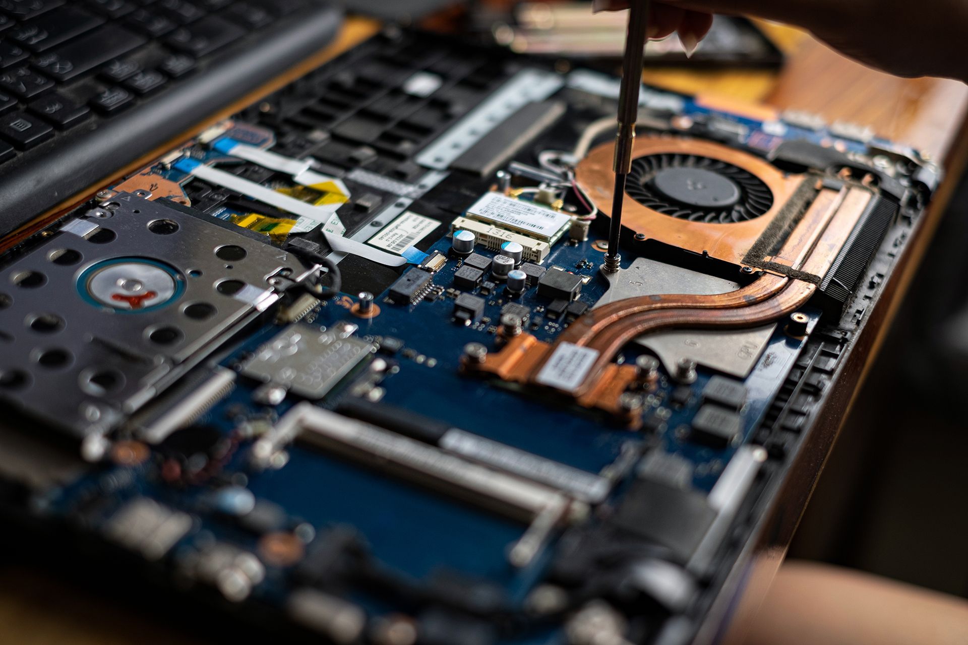 A person is fixing a laptop computer with a screwdriver