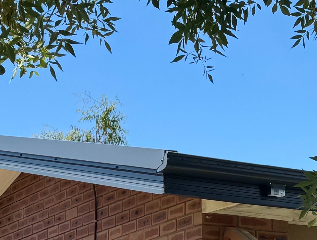 A Brick Building With a Black Gutter and a Blue Sky in the Background — CBR Maintenance In Curtin, ATC