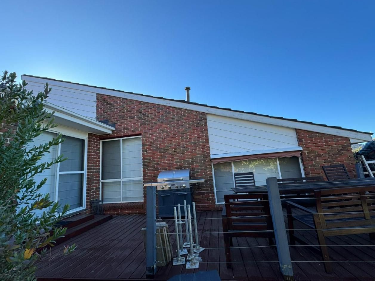 A Brick House with A Wooden Deck and A Grill — Canberra Complete Maintenance in Curtin, ACT