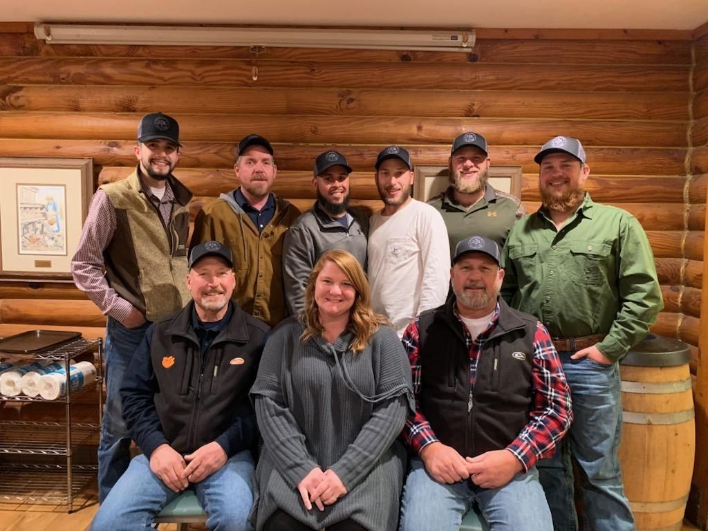 A group of people are posing for a picture in front of a log cabin.