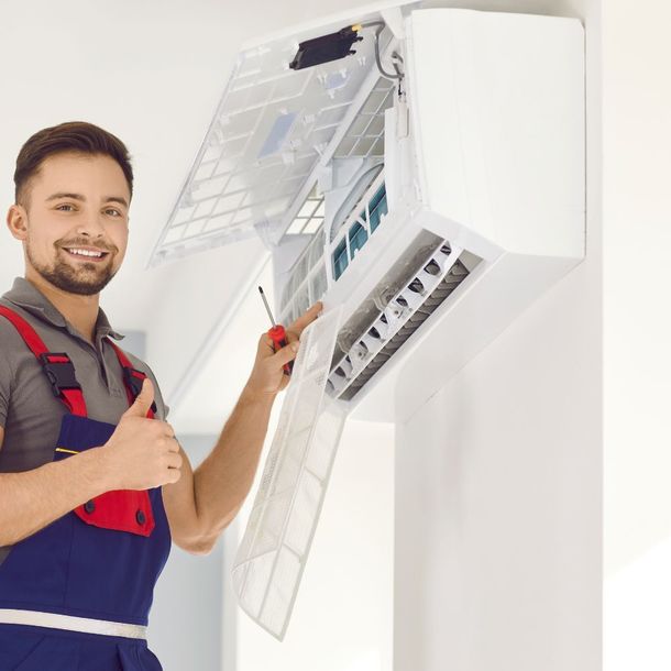 A man is working on an air conditioner and giving a thumbs up.