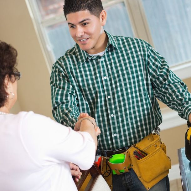 A man in a green plaid shirt shakes hands with a woman