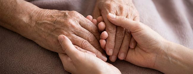 Hands gently clasped together on a soft blanket, suggesting comfort and support