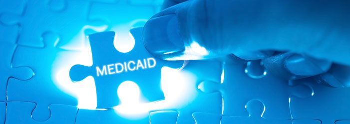 A person is putting a puzzle piece with the word medicaid on it.