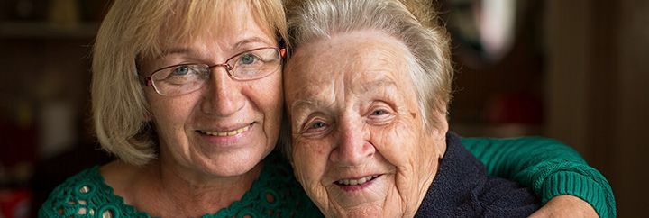 Two older women are hugging each other and smiling for the camera.