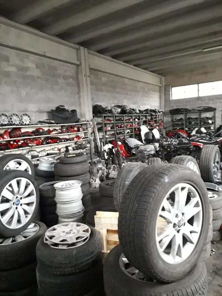 Magazzino pieno di pile di pneumatici e cerchioni usati su scaffali e sul pavimento