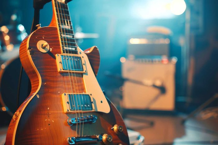 vintage brown electric guitar on stage, blue and white stage lighting. Close-up of a vintage brown electric guitar on stage, blue and white stage lighting.