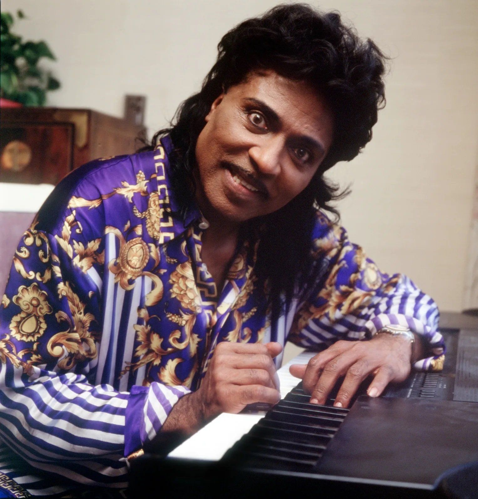 A man in a purple striped shirt is playing a piano